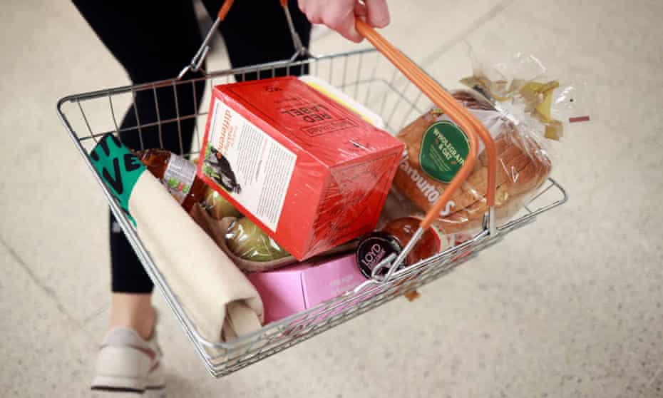 A person carries a shopping basket at a Sainsbury's store