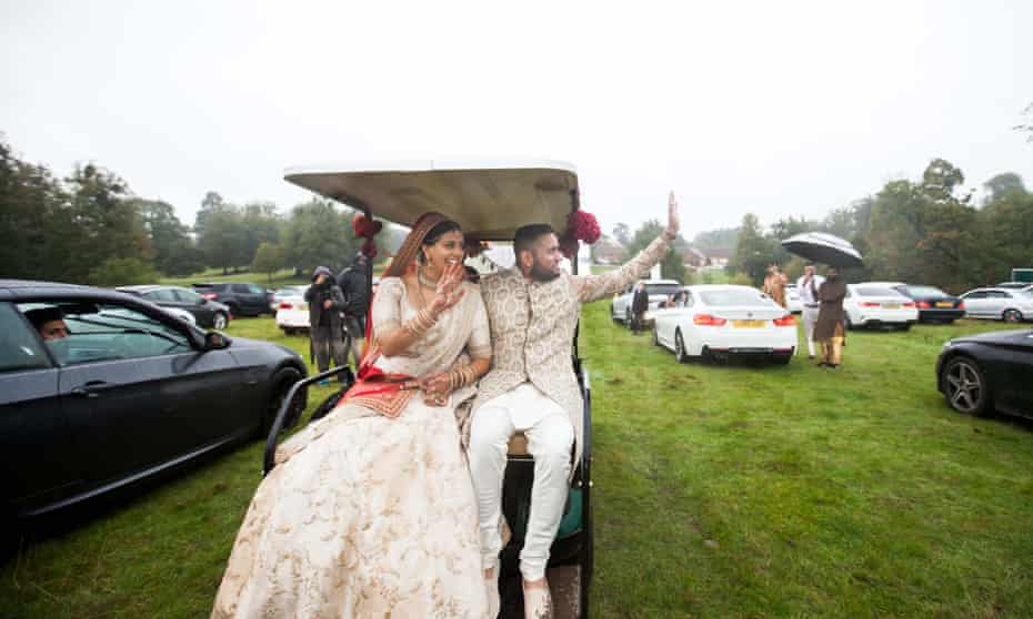 Roma Popat and Vinal Patel wave at guests from their golf buggy.