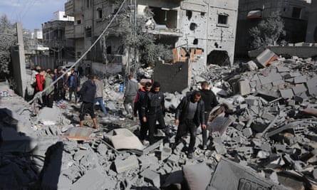 Surviving family members collect belongings from a destroyed building in the Nuseirat refugee camp in Gaza City on 13 February.