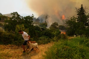 A man leads two goats away from a wildfire