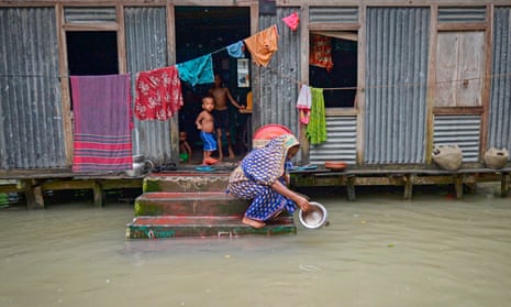 A woman washes a pot in flood water in Sreenagar, Bangladesh, after heavy monsoon rain last year.