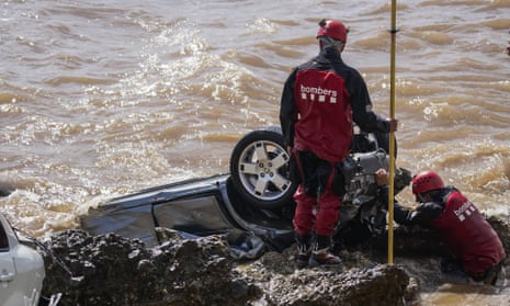 Firefighters check wrecked cars stuck on the shore of the seaside town of Alcanar in north-east Spain