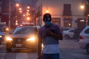 A pedestrian walks in the street wearing a face mask as volcanic dust fills the air in Atlixco