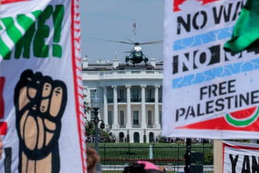people hold signs as a helicopter flies overhead