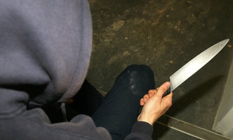 A man in a hoodie holding a knife