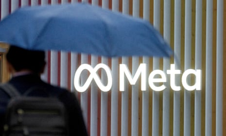 A man with a blue umbrella walks by the logo of Meta Platforms.