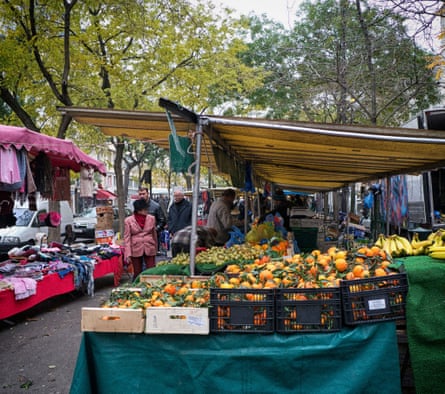 Stalls full of clothing and fruit at a Ménilmontant street market.