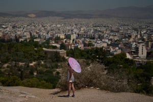 A tourist holds a parasol while standing on a hill overlooking the city
