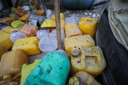 20-30 plastic water holders abandoned in the dirt, some spattered with blood