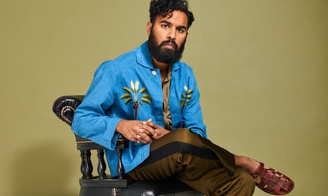 Himesh Patel in a vibrant blue shirt and sitting on a chair with one leg  half over the other