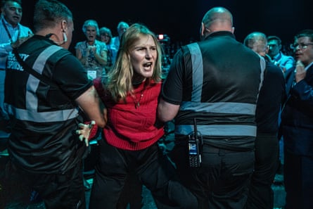 A woman is hauled away by security personnel after protesting at the Reform UK conference.