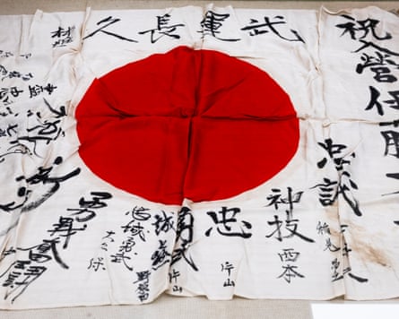 A white flag with a bright red circle in the centre has messages in black Japanese calligraphy around the red circle.