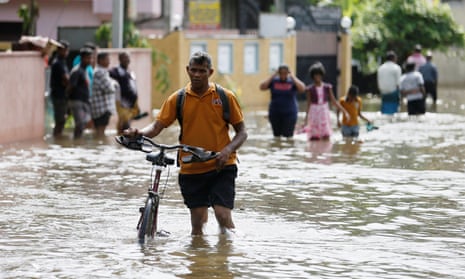A man pushes his bike through a flooded road in Dodangoda village in Kalutara, Sri Lanka. 