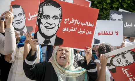 Supporters of Nabil Karoui hold up placards with his face