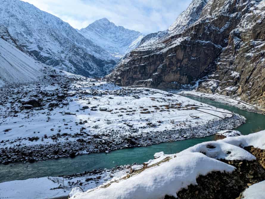 A river runs through a steep valley between snowy, jagged peaks 
