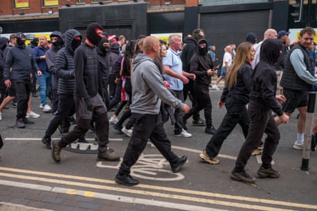 A large group of mostly male marchers including some in balaclavas