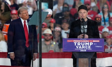 Donald Trump listens as Elon Musk speaks during a campaign rally