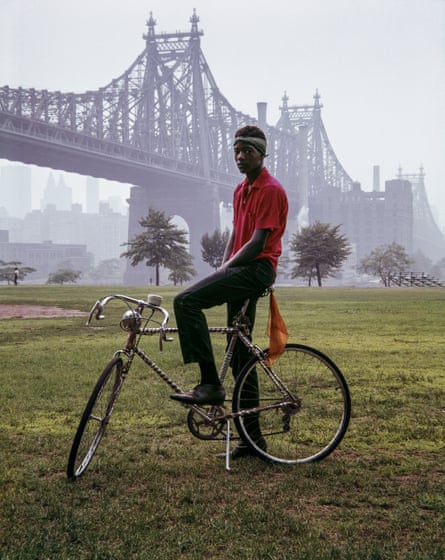 A young man on a racing back in a park with the Queensboro Bridge in the background