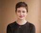 Author Emily St John Mandel, with short brown hair and a necklace, smiles gently