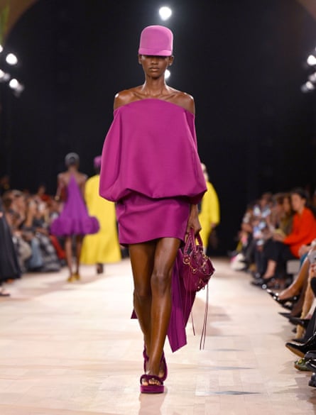 A model wears a violent purple cap and sack-inspired short dress in the same colour with a matching handbag