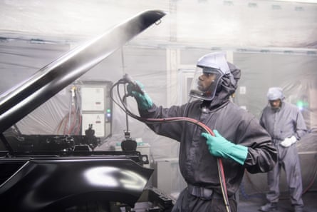 Two men in haz maz suits spray paint on a car in Jaguar Land Rover’s Advanced Manufacturing Facility in Solihull, Birmingham