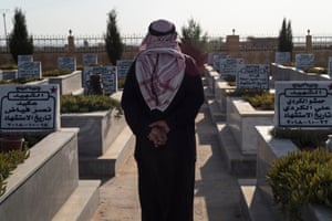 A man among the graves in Hasakah martyrs cemetery where several fighters, who died in Turkish attack in October 2019, are buried.