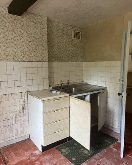 Decrepit-looking kitchen sink area, with tiled floor and black mould on ceiling