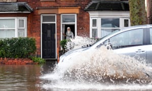 A man watches a car drive through a flooded street in Alum Rock, Birmingham.