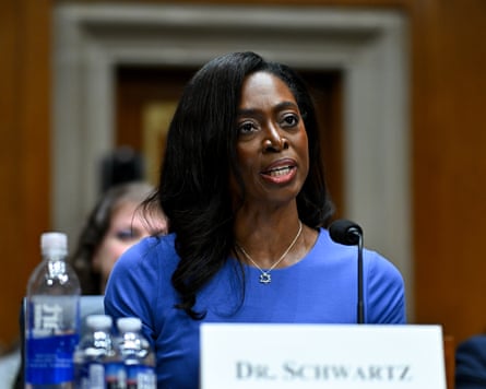 Portrait of Erica Schwartz wearing a blue top attending an official event with her name card in front of her.