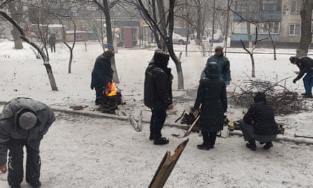 Occupied Mariupol, March 2022, locals cook food in the yard of a high-rise building