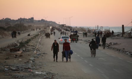 People walk along a coastal path as the sun sets in Gaza