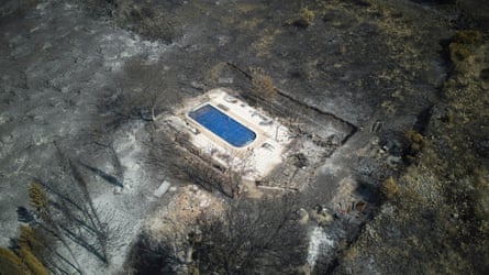 A swimming pool is all that’s left in a setting of grey, desolate charred ground and burned tree trunks