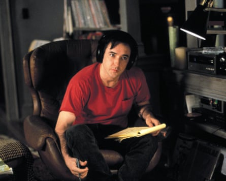 He sits in a leather armchair with headphones on, with hi-fi equipment and vinyl records