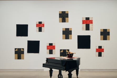 paintings of orange and black crosses on wall behind piano