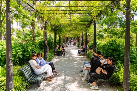People sitting on benches in the Giardini Reali in Venice, Italy.