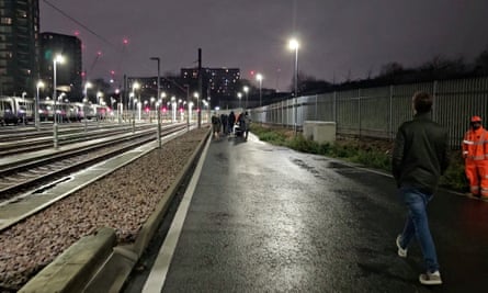 Passengers walk along a platform after being evacuated from trains stuck on the Elizabeth line
