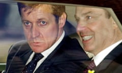 Close-up of faces of Alastair Campbell and Tony Blair, snapped sitting together in the back of a car through the window, 2001; Campbell looks serious and intense, while Blair is grinning but not necessarily happily