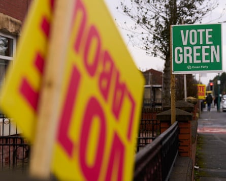 An upside down Vote Labour sign with a “vote green” placard in the background