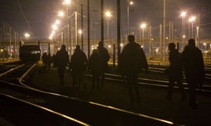 Refugees walk on the railway tracks leading to the entrance of the Channel tunnel in Calais.