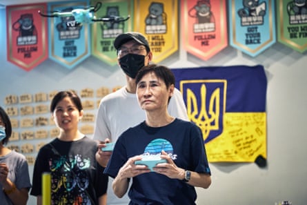 A woman flies a drone as others watch on