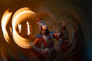 A woman in traditional clothes holding a pipe, as light swirls around her