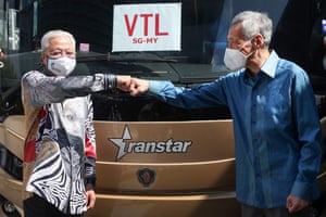 Singapore’s Prime Minister Lee Hsien Loong (R) fist-bumping with his Malaysian counterpart Ismail Sabri Yaakob in front of a cross-border bus at the launch of the vaccinated travel lane (VTL) between Singapore and Malaysia.