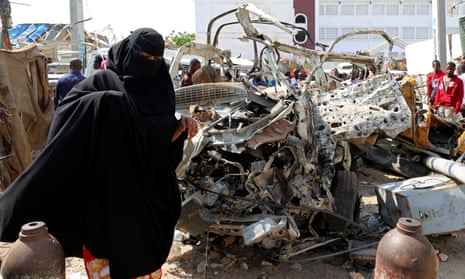a woman walks past the wreckage of a bomb blast in Mogadishu