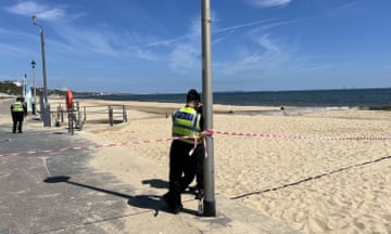 A police officer behind police tape on Bournemouth beach