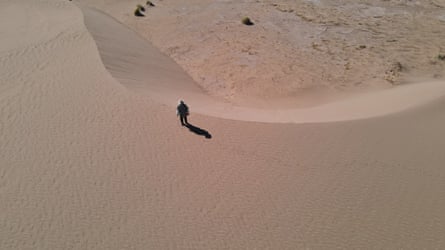 An aerial view of a man in a large expanse of sand.