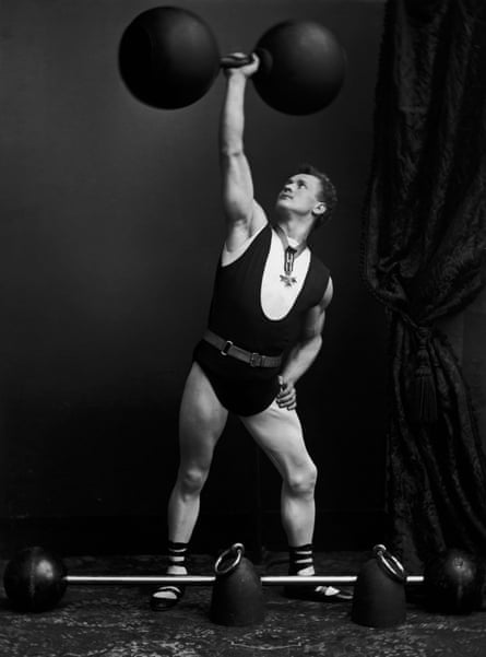 Eugene Sandow holds up what appears to be a massive and very heavy dumb-bell