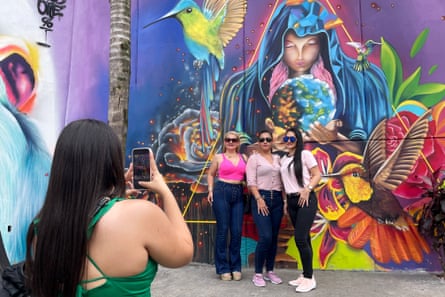 Tourists take photos in front of a wall mural in Comuna 13