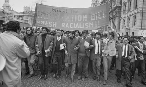 A black and white photograph of a demonstration against apartheid, with men linking arms and carrying a banner