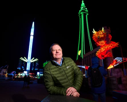 Richard Williams smiles as he stands outside, with the Blackpool Illuminations behind him