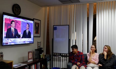 three people watch the debate on a TV